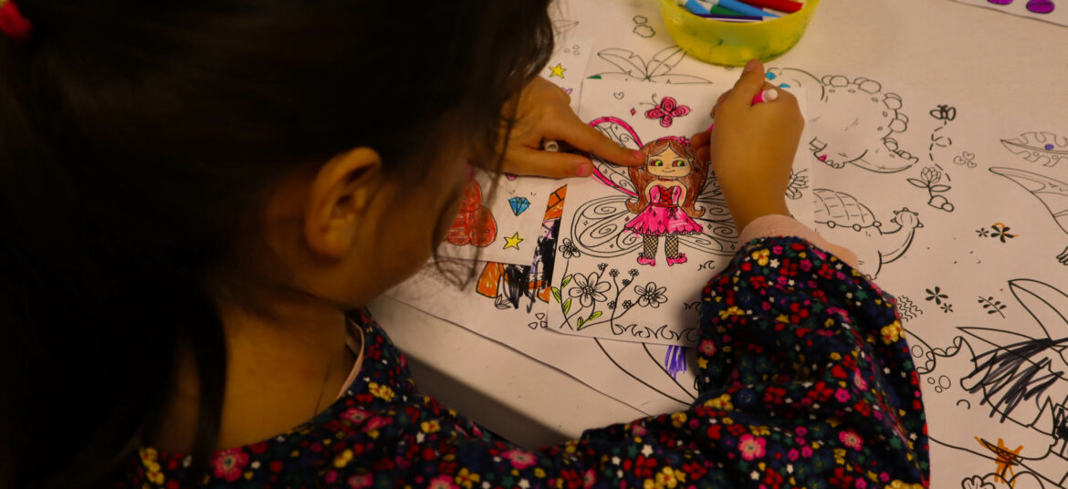 Enfant coloriant un dessin de fée lors d’un atelier créatif aux Coqs Rouges.