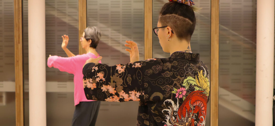 Deux personnes pratiquent des mouvements lents et fluides de Tai Chi dans un espace calme.