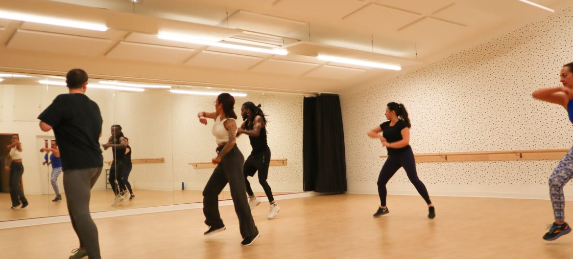 Groupe de personnes suivant un cours de danse dans une salle avec miroir
